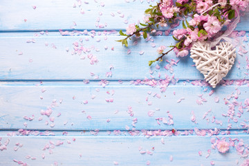 Pink  sakura flowers and white  decorative heart on blue wooden planks.