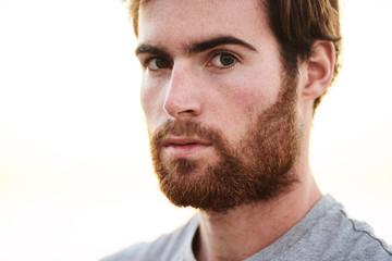 Obraz premium close up face shot of white bearded male looking straight into camera with serious facial expression.