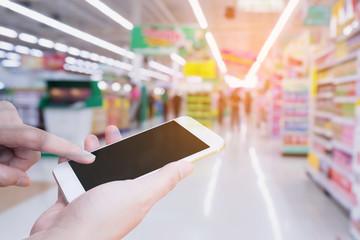 Woman using mobile smartphone while shopping in supermarket store