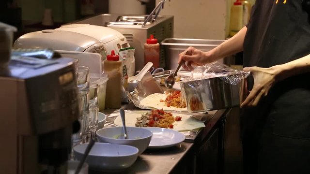 An Asian man preparing Mexican food, making delicious burritos in the kitchen of a Mexican restaurant-Dan
