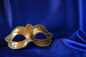 gold venetian mask on blue silk background