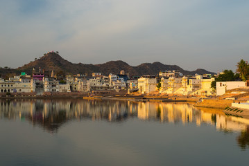 Fototapeta na wymiar Cityscape at Pushkar, Rajasthan, India. Temples, buildings and ghats reflecting on the holy water of the lake at sunset.