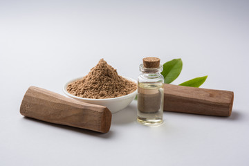 Chandan or sandalwood powder with traditional mortar, sandalwood sticks, perfume or oil and green...