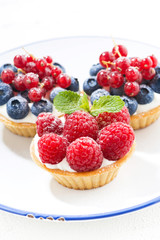 mini cakes with cream and berries on plate, vertical