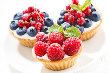 mini tarts with cream and fresh berries on white background, closeup