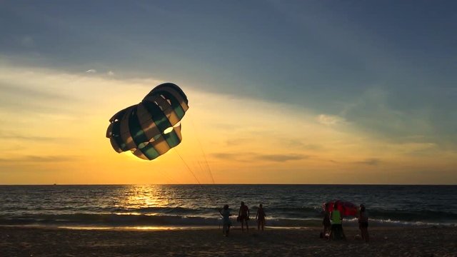 Man Holding a Parachute in the Wind on the Beach During Sunset. Karon beach, Phuket, Thailand. HD silhuette slowmotion.