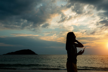 Fototapeta premium Silhouette women watching the sunset at the beach.