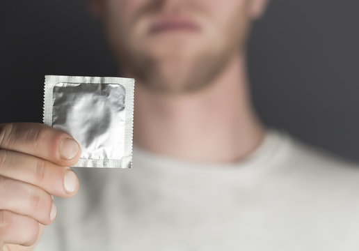 Hand of  young man holds packing of condoms. Cropped image
