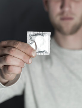 Hand of  young man holds packing of condoms. Cropped image