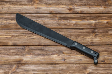 Machete for cutting grass on wooden background