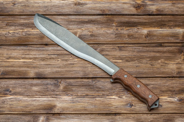 Machete for cutting grass on wooden background