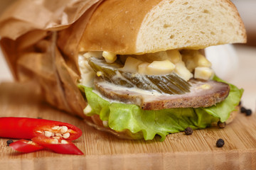 Big sub sandwich baguette with ham on wooden cutting board