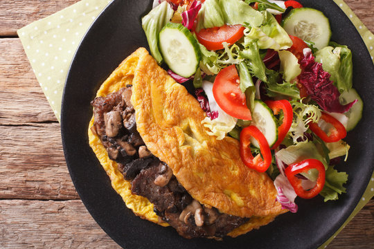 Austrian cuisine: Imperial cutlet with mushrooms, scrambled eggs and salad closeup. horizontal top view