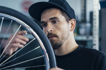 Close-up of worker checking bicycle wheel - 137302516