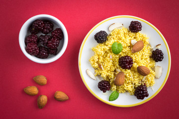Puree of Millet Grains with Blackberries and Almonds on Wine Coloured Background