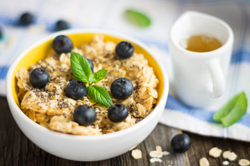 Porridge - Oat Flakes with Blueberries and Mint Leaves on Tablecloth and Wooden Background