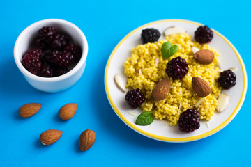 Puree of Millet Grains with Blackberries and Almonds on Blue Background.