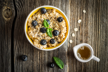 Top View Porridge - Oat Flakes with Blueberries and Mint Leaves on Wooden Background