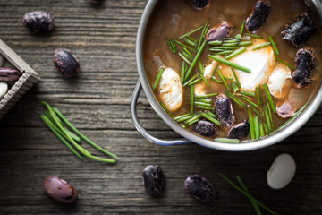 Rustic Food. Bean Soup with Garlic and Chives in Pot Detail on Wooden Background.