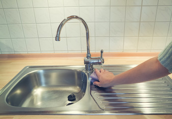 Frau putzt Spülbecken in der Küche - Hygiene