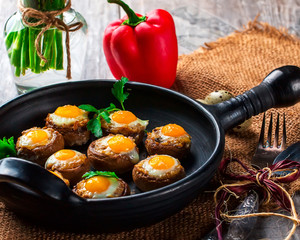 Mushrooms stuffed with quail egg on black pan