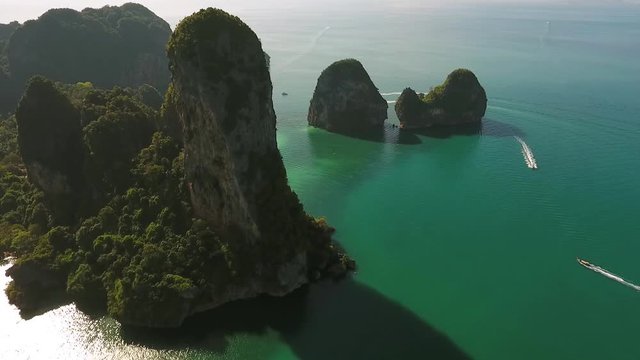 Big Rock Mountain with many Long Tail Boats near Railey beach, Krabi, Thailand. HD slowmotion aerial view.
