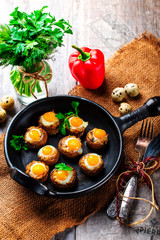 Mushrooms stuffed with quail egg on black pan