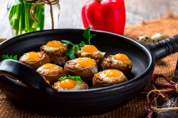 Mushrooms stuffed with quail egg on black pan
