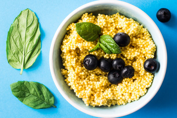 Puree of Millet Grains with Blueberries on Blue Background. Overhead Shot.