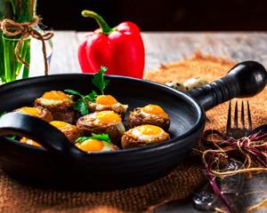 Mushrooms stuffed with quail egg on black pan
