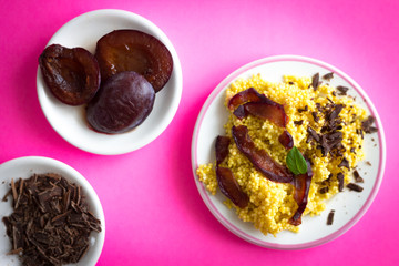 Puree of Millet Grains with Plums, Chocolate and Walnuts and Raw Ingredients on Pink Background