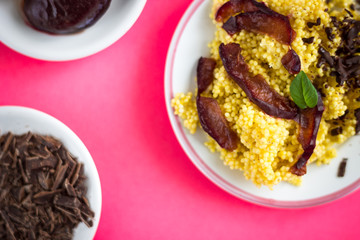 Puree of Millet Grains with Plums, Chocolate and Walnuts and Raw Ingredients on Pink Background Detail Photo.