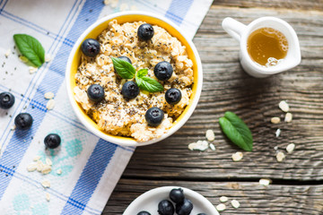 Porridge - Oat Flakes with Blueberries and Mint Leaves on Tablecloth and Wooden Background