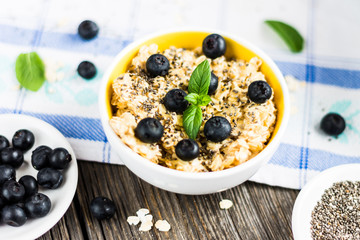 Oat Flakes with Blueberries and Ingredients on Tablecloth and Wooden Background