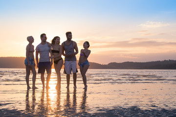 Fototapeta premium Young People Group On Beach At Sunset Summer Vacation, Happy Smiling Friends Walking Seaside Sea Ocean Holiday Travel