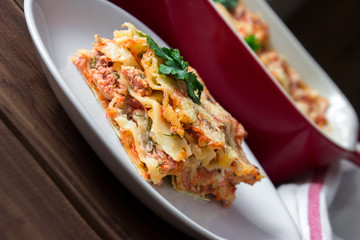 Close-up of a traditional lasagna topped with parskey leafs served on a white plate