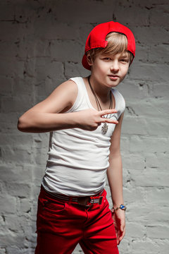 Portrait of cool young hip hop boy in red hat and red pants and white shirt in the loft
