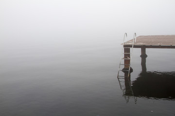 A wooden pier and stairs to sea in a foggy day.
