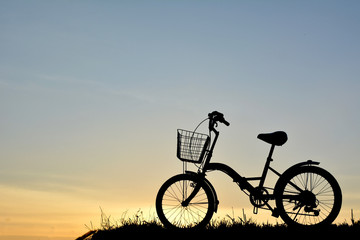 Obraz premium Silhouette of bicycle on grass with the sky sunset