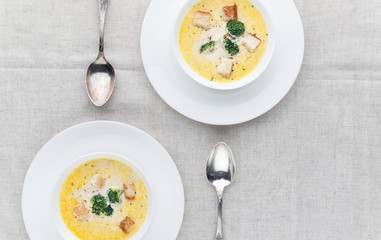 cheese soup with broccoli in a white plate on a white linen tablecloth