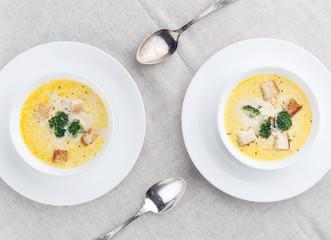cheese soup with broccoli in a white plate on a white linen tablecloth