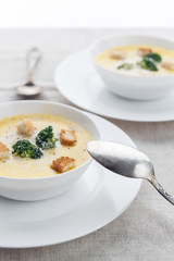 cheese soup with broccoli in a white plate on a white linen tablecloth