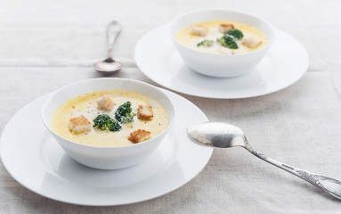 cheese soup with broccoli in a white plate on a white linen tablecloth