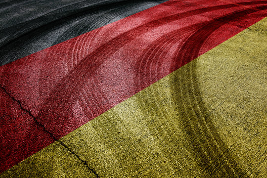Painted Germany flag on the asphalt road with crossing of tires tracks. Conceptual motorsport competition background.