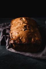 Fresh bread with dried fruits on dark rustic background. Side view