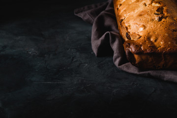 Fresh bread with dried fruits on dark rustic background. Side view with copy space