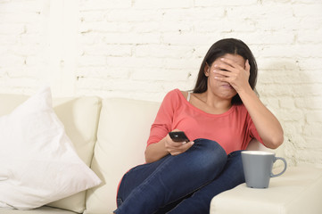 Naklejka premium latin woman sitting at home sofa couch in living room watching television scary horror movie