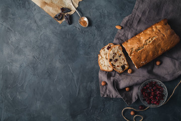 Baked cake with dried fruits and nuts on rustic background. Top view with copy space. - obrazy, fototapety, plakaty
