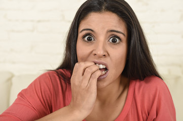 Naklejka premium latin woman sitting at home sofa couch in living room watching television scary horror movie