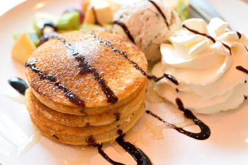 Stack of pancakes with fresh fruits, ice cream and whipped cream